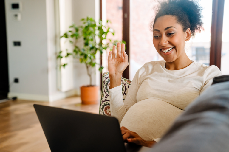 pregnant woman waving at laptop screen